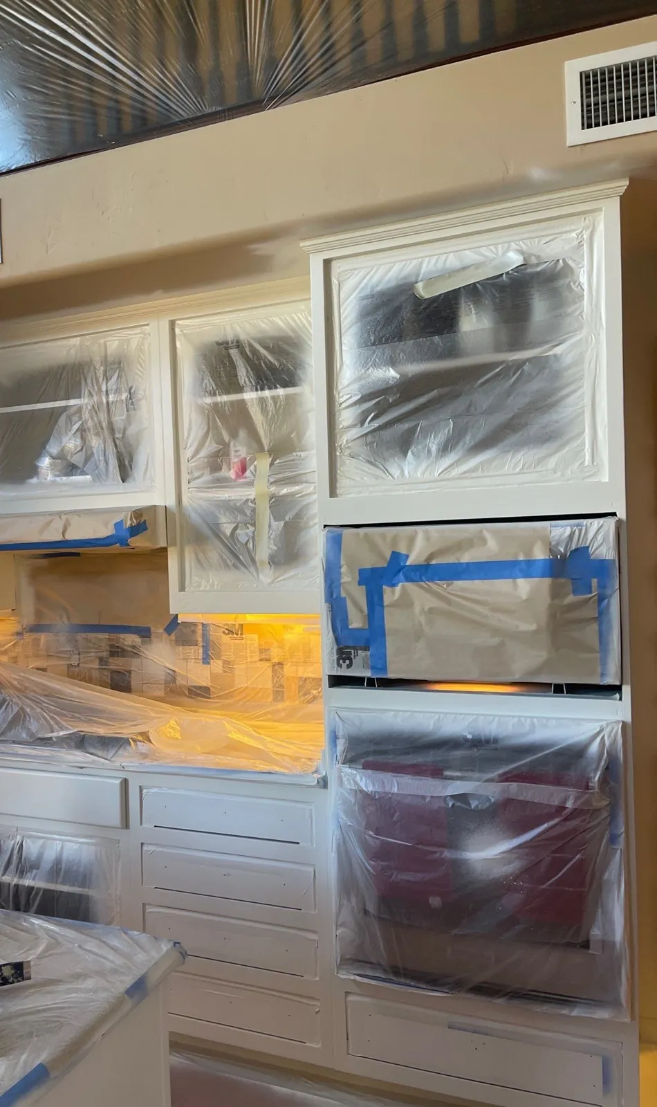 Kitchen cabinet boxes and face frames painted white, with appliances still masked