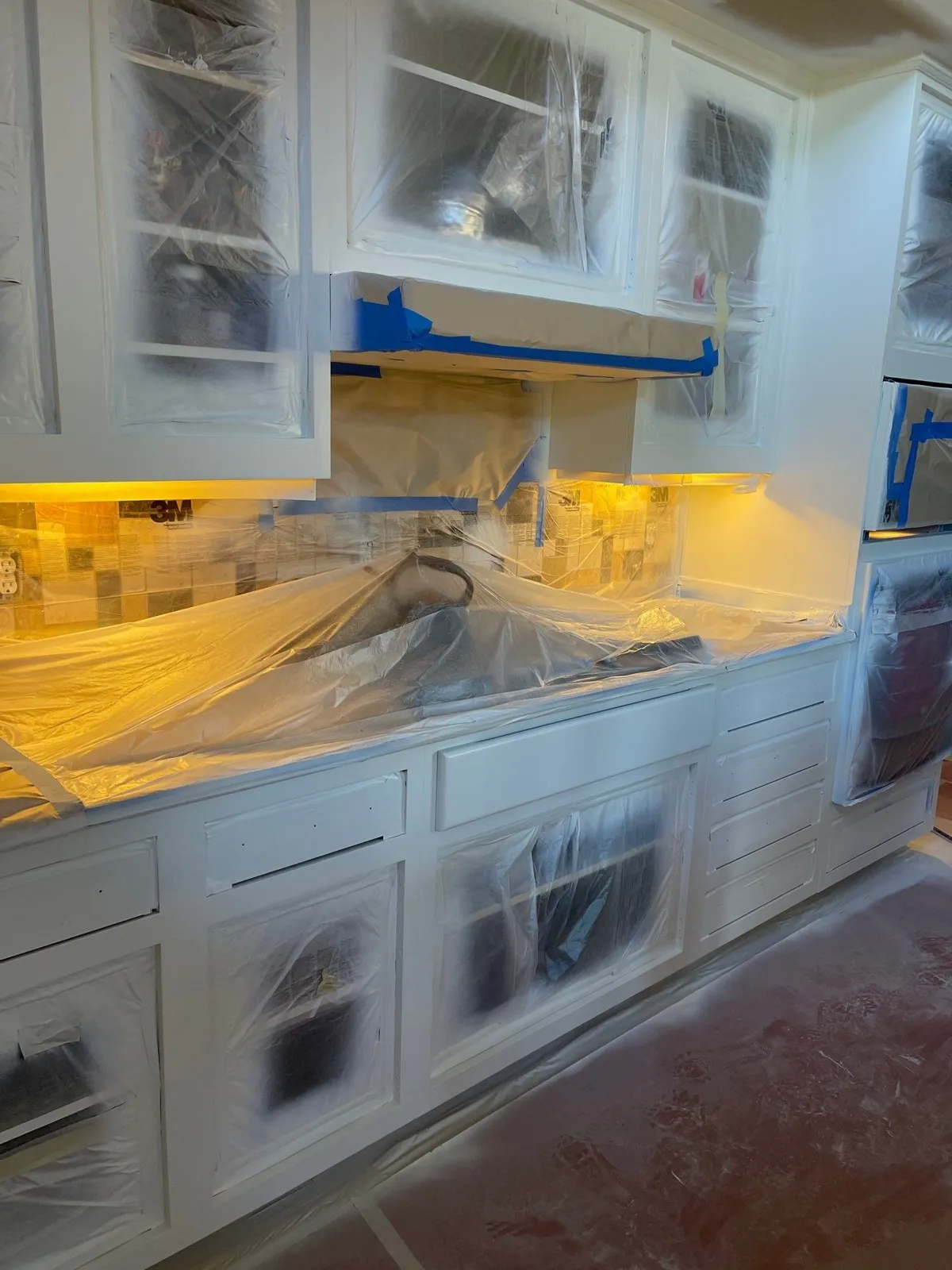 Run of white-painted lower and upper cabinets with countertop and glass fronts still under plastic