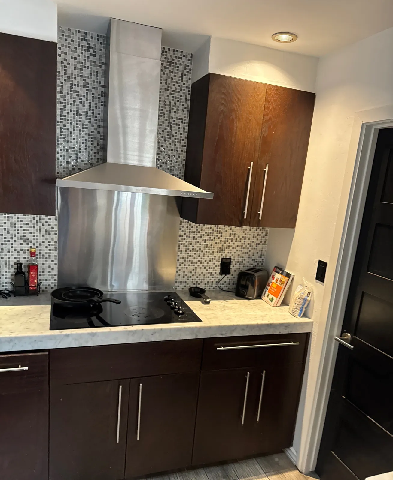 Espresso wood-grain cabinets flanking a stainless range hood over a cooktop