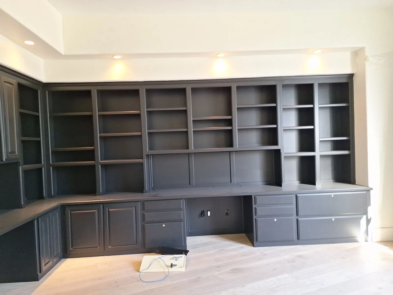 The same office built-ins painted black: bookcases, desk, and file drawers along a light oak floor