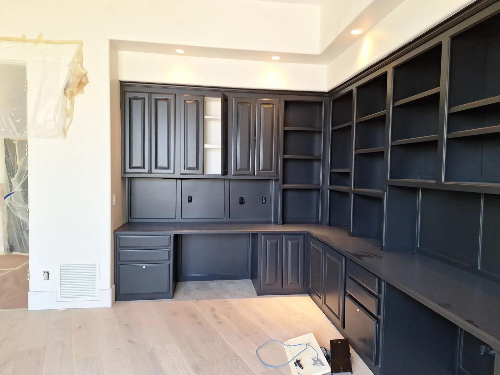 Corner view of black-painted built-in cabinets and bookshelves with raised-panel upper doors
