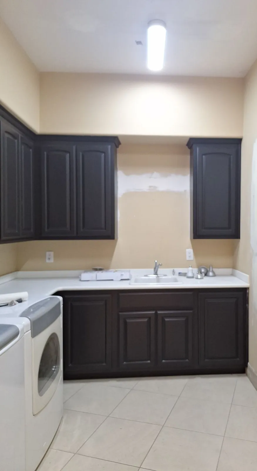 Laundry room with raised-panel upper and lower cabinets painted black above a white countertop