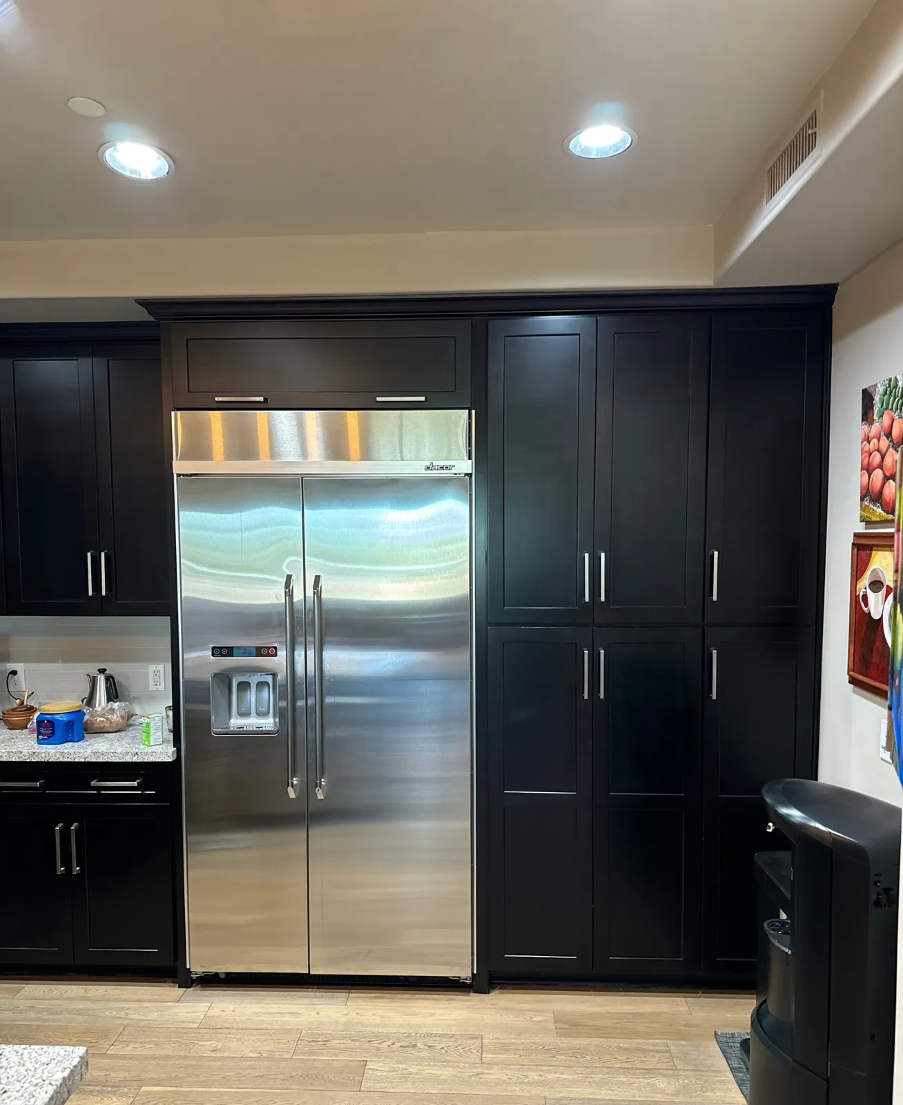 Espresso shaker pantry towers surrounding a built-in stainless refrigerator