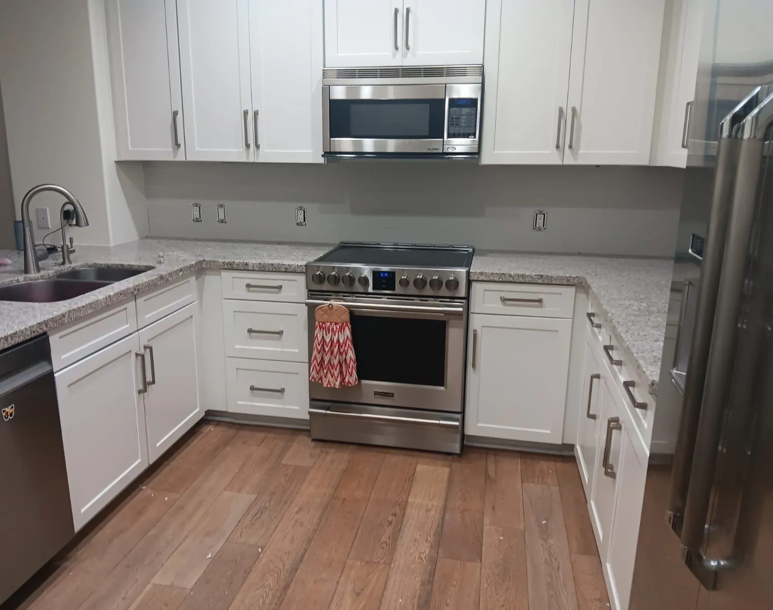 U-shaped kitchen with white shaker cabinets, granite counters, and stainless appliances